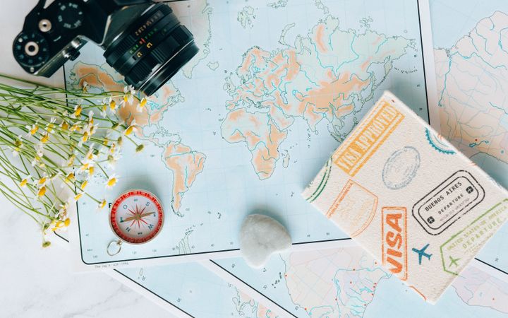 World map with a passport, visa stamps and a camera