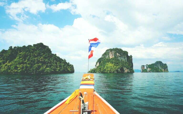 Long-tail boat sailing towards lush islands in the Andaman Sea on a sunny day