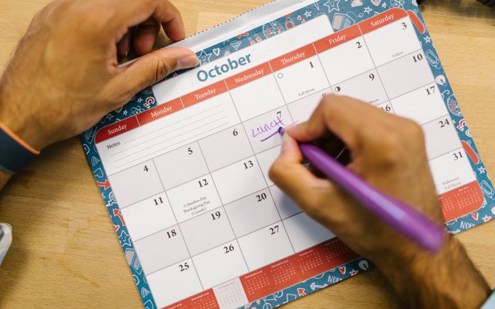 Hand marking travel dates on a wall calendar