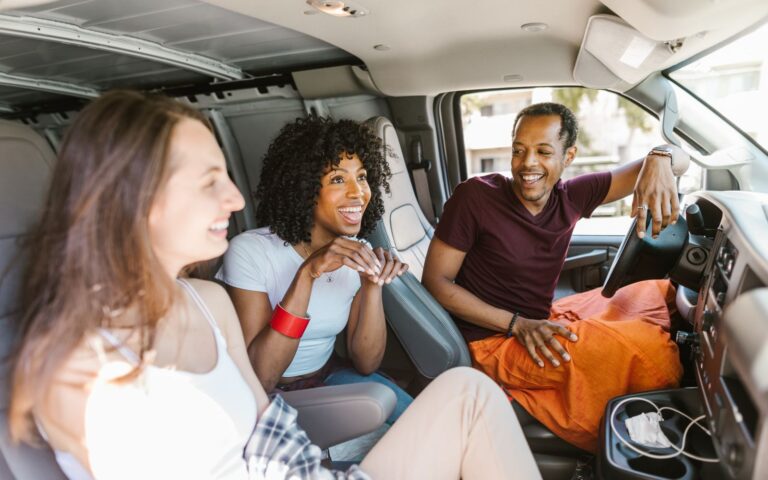 Group of friends laughing and enjoying a road trip inside a van. Perfect for travel and lifestyle themed projects