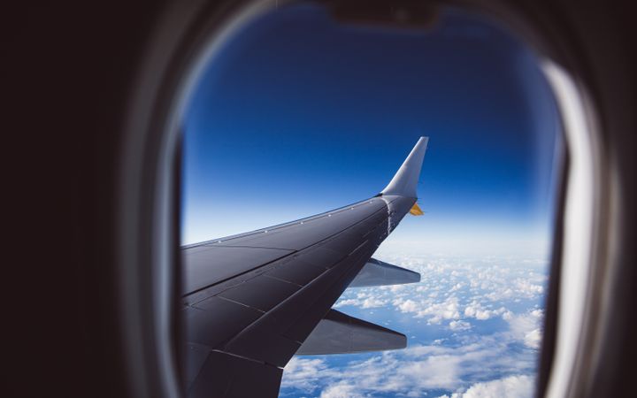 Airplane wing above the clouds seen from a window seat
