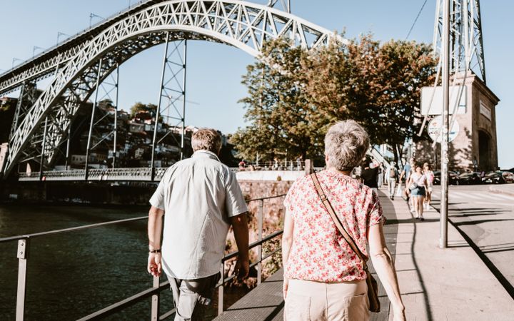 Senior couple walking along a riverside street in Porto