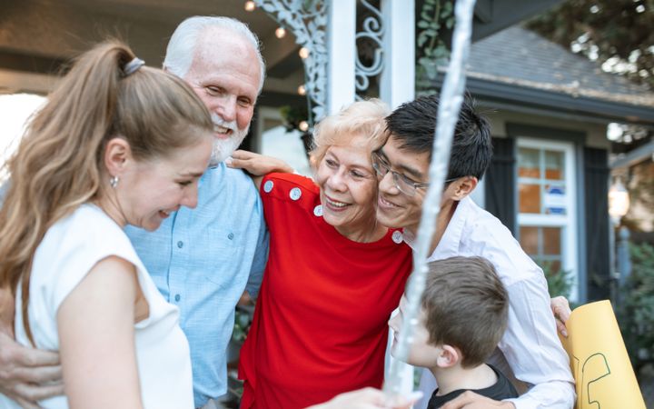 Family greeting grandparents with hugs at the front door